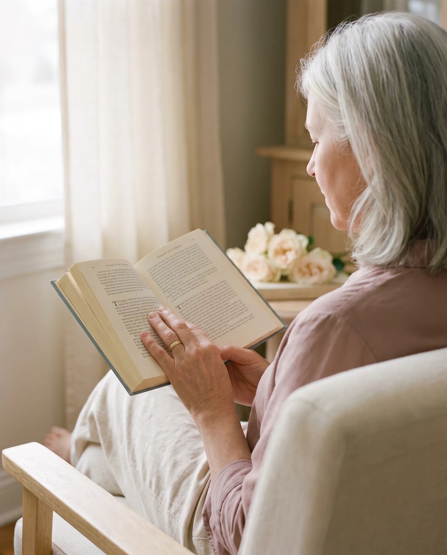 A woman reading a Ploughman Press book by the window